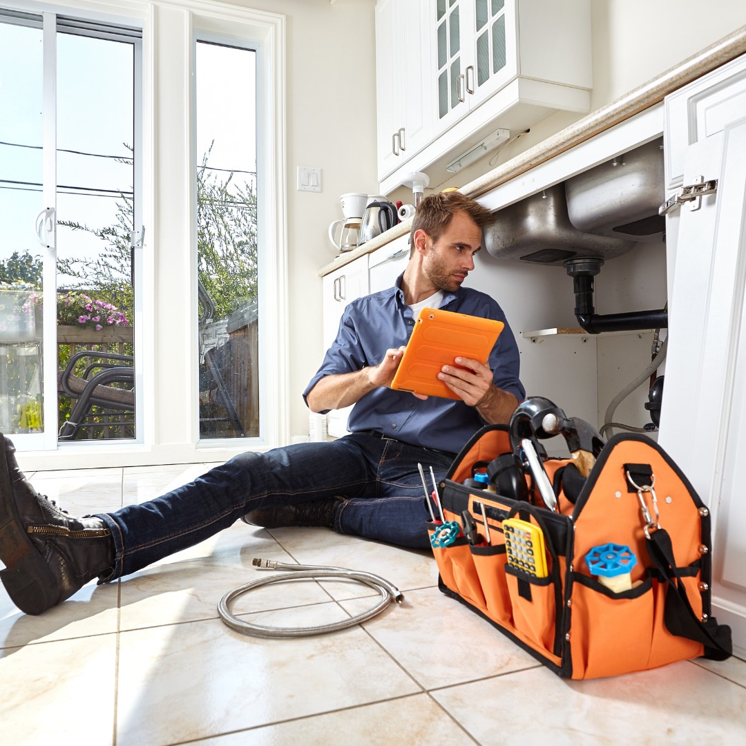 Basin Plumbing plumber repairing pipes under a kitchen sink in Odessa, TX